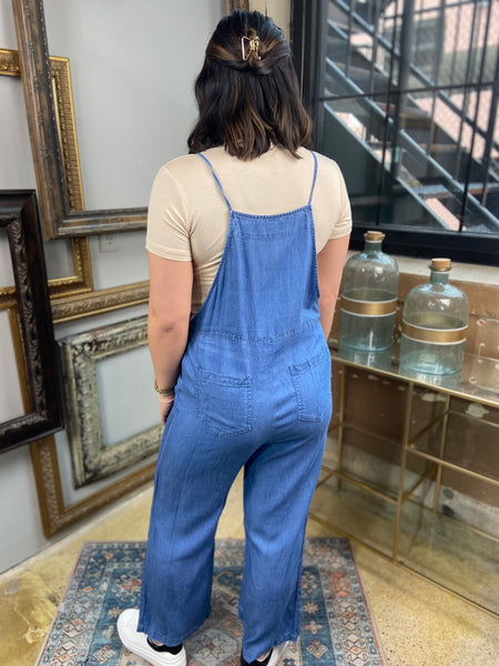 light blue denim overalls jumpsuit pockets long wide leg spaghetti straps back view