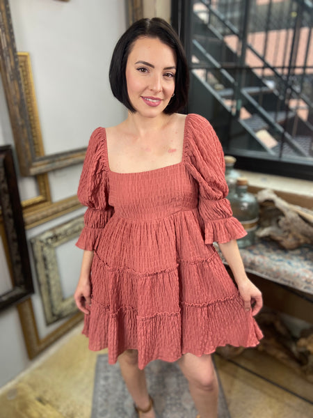 Crafted from a textured gingham fabric, this mini dress boasts a classic peasant dress design with multiple ruffles and gathered sleeves. The back features ties for a flattering fit. Perfect for any summer occasion, this gingham dress is both stylish and comfortable."





Textured gingham peasant dress

Classic and feminine silhouette

Lightweight and breathable fabric